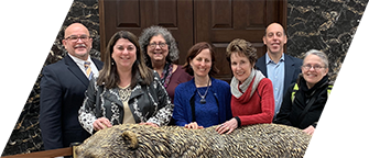 Take Action DVU board members and founders stand smiling with their hands on a statue of a bear in front of the Governor’s office in the California State Capitol.