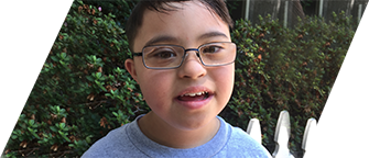 A young boy with a disability smiles at the camera.